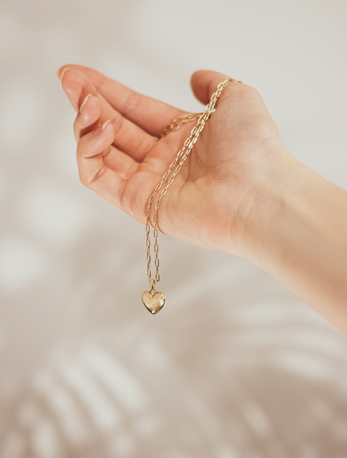 A hand holding a gold pendant on a chain